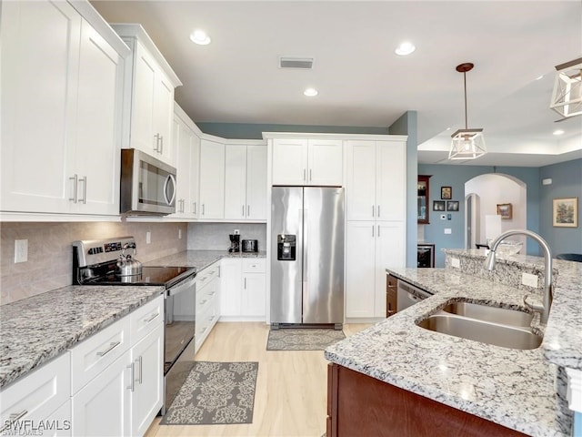 kitchen featuring sink, decorative light fixtures, white cabinetry, tasteful backsplash, and appliances with stainless steel finishes