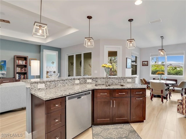 kitchen featuring dishwasher, decorative light fixtures, and light stone countertops