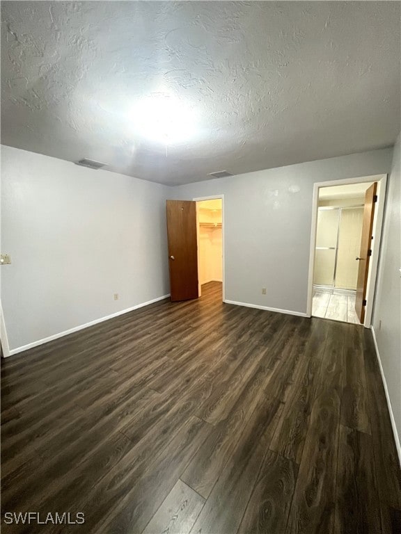 spare room with a textured ceiling and dark hardwood / wood-style flooring