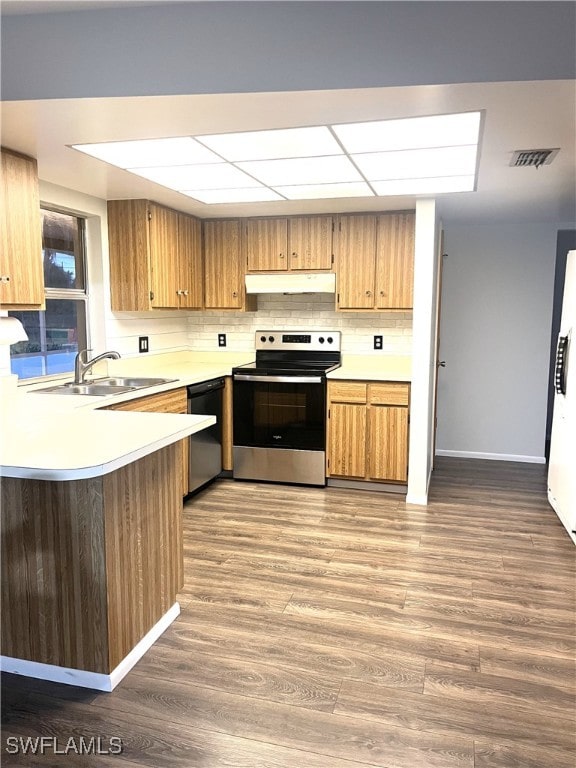 kitchen featuring dishwashing machine, wood-type flooring, sink, kitchen peninsula, and stainless steel range with electric stovetop