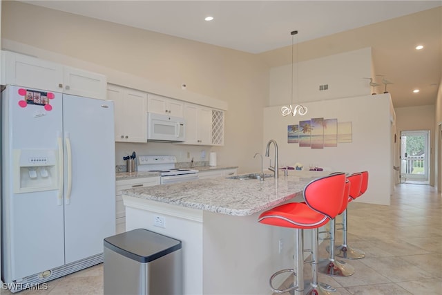 kitchen featuring sink, white cabinetry, hanging light fixtures, an island with sink, and white appliances