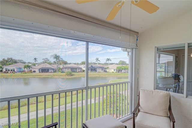 sunroom / solarium with lofted ceiling, ceiling fan, and a water view