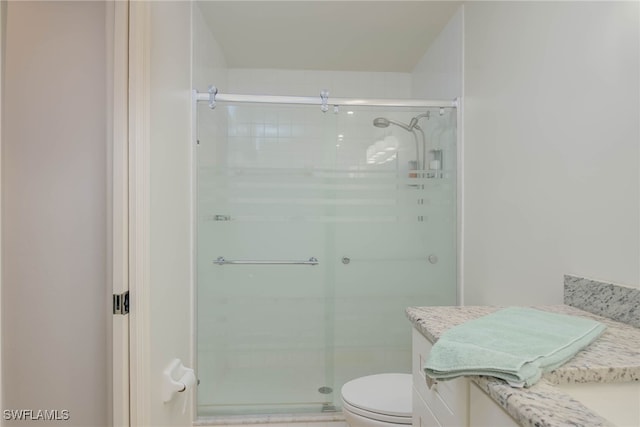 bathroom featuring vanity, walk in shower, and toilet