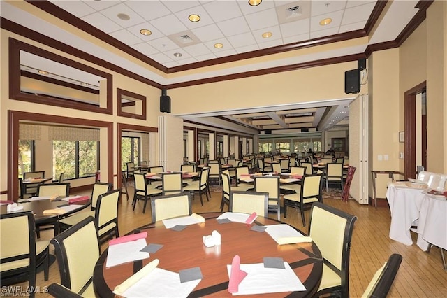 dining room featuring crown molding, wood-type flooring, and a towering ceiling