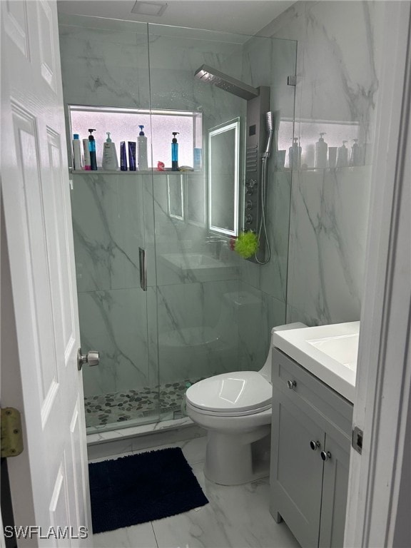 bathroom featuring a shower with door, vanity, and toilet