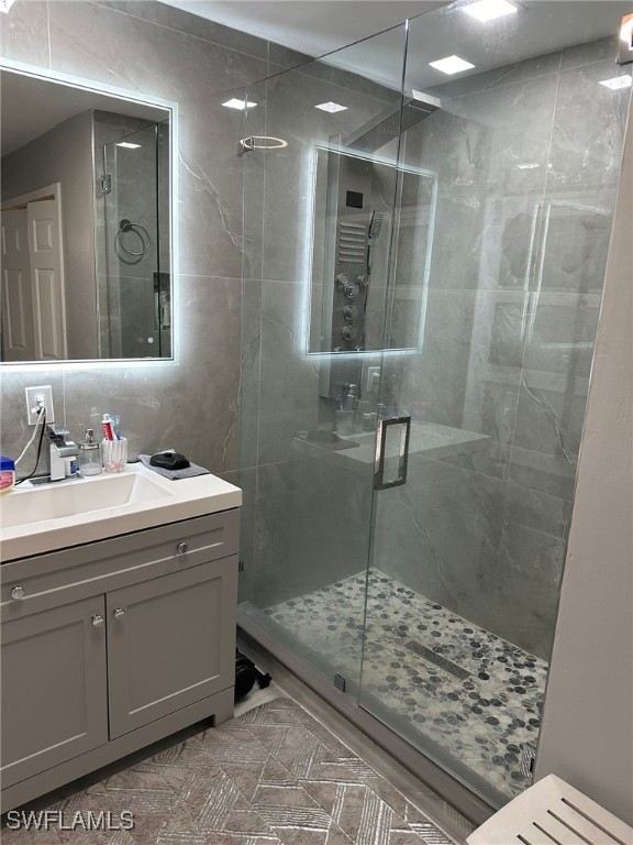 bathroom with walk in shower, vanity, and decorative backsplash