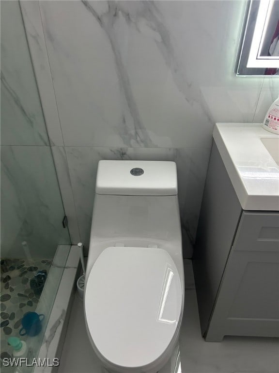 bathroom featuring tile walls, vanity, a shower, and toilet