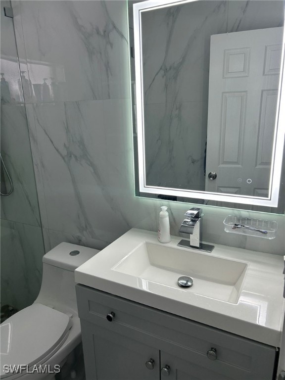 bathroom with toilet, vanity, and tile walls