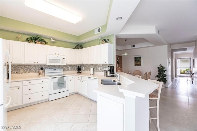 kitchen featuring white cabinetry, kitchen peninsula, white appliances, a breakfast bar, and sink