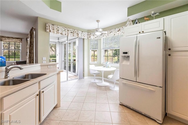 kitchen featuring light tile patterned floors, white cabinetry, ceiling fan, white fridge with ice dispenser, and sink