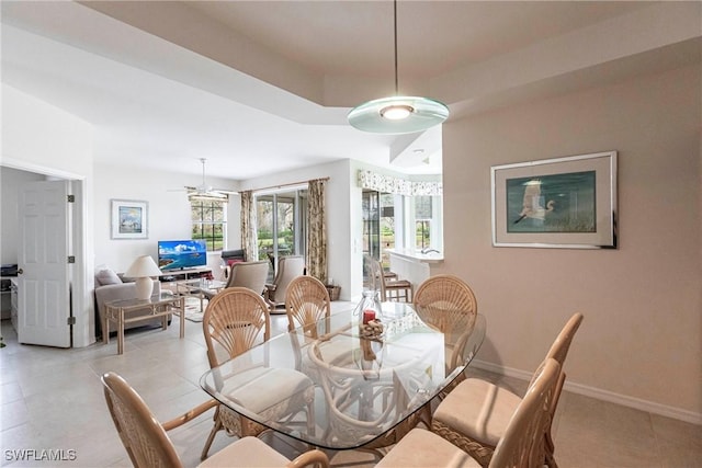 dining space with ceiling fan and a raised ceiling