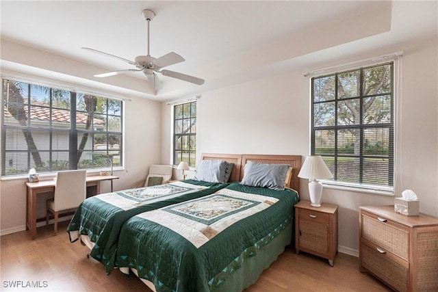 bedroom featuring ceiling fan, multiple windows, and light hardwood / wood-style flooring