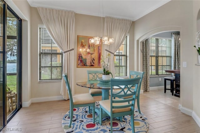 dining space featuring light wood-type flooring, an inviting chandelier, baseboards, and crown molding