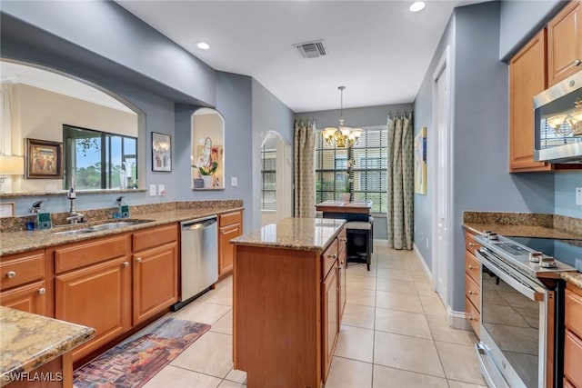 kitchen featuring light stone countertops, a sink, visible vents, appliances with stainless steel finishes, and a center island