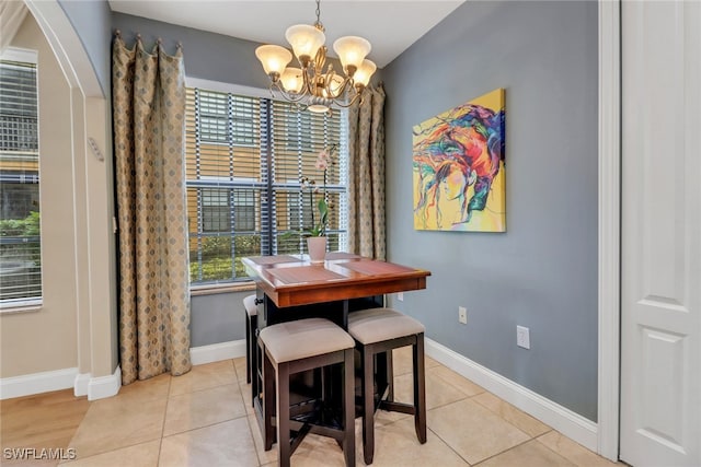 dining space with a chandelier, light tile patterned flooring, and baseboards