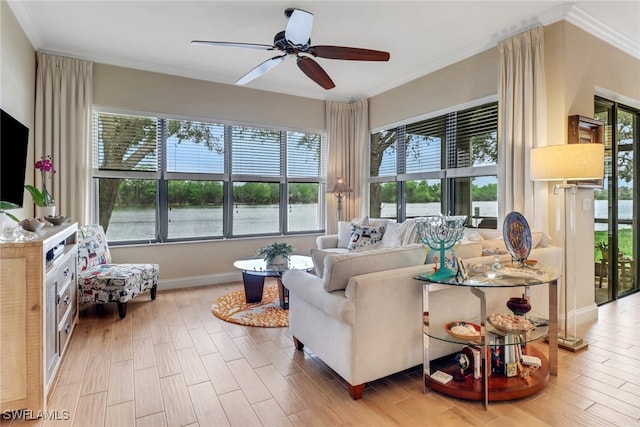 living room featuring a ceiling fan, crown molding, baseboards, and wood finished floors