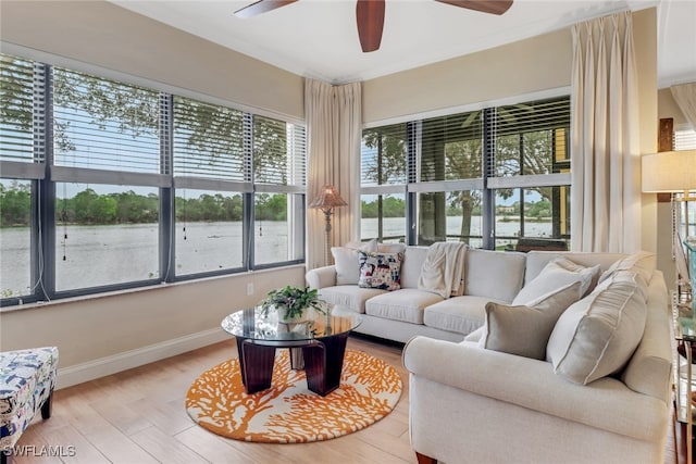 living room featuring light wood-type flooring, ornamental molding, and a water view