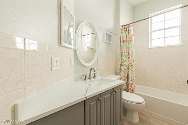 full bathroom featuring shower / bathtub combination with curtain, vanity, tile walls, toilet, and hardwood / wood-style flooring