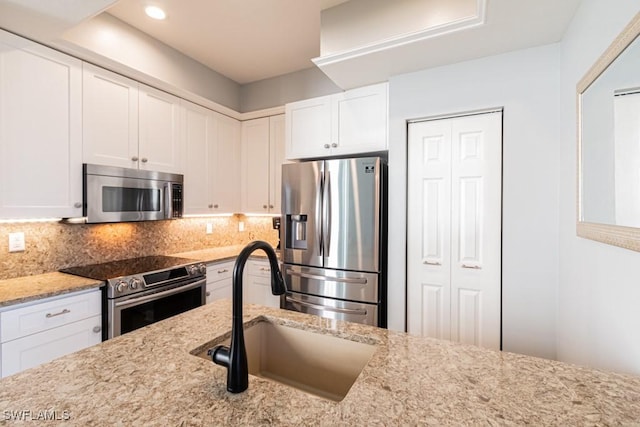 kitchen featuring white cabinets, decorative backsplash, appliances with stainless steel finishes, and sink