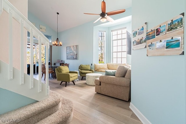 living room with ceiling fan with notable chandelier and light wood-type flooring