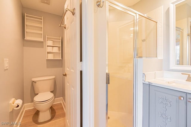 bathroom featuring toilet, vanity, a shower with shower door, and hardwood / wood-style flooring