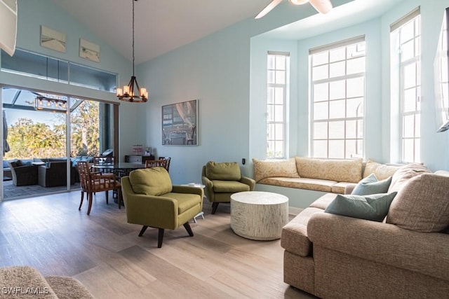 living room with high vaulted ceiling, ceiling fan with notable chandelier, and hardwood / wood-style flooring