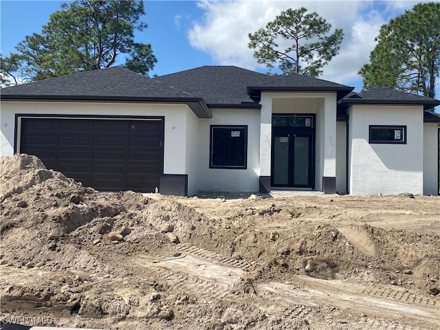 view of front facade featuring roof with shingles, an attached garage, and stucco siding