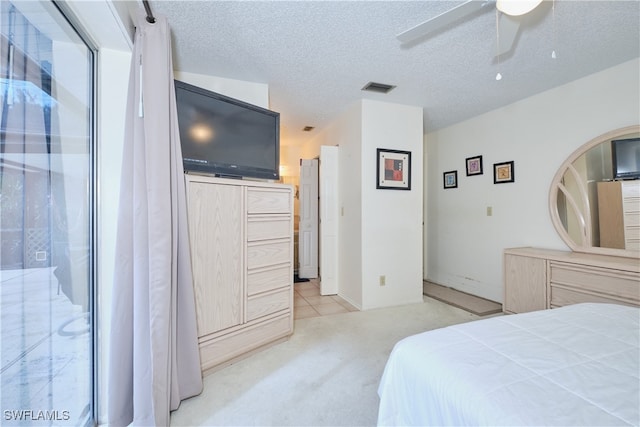 bedroom with light carpet, ceiling fan, and a textured ceiling