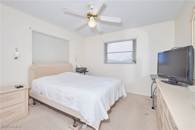 bedroom with light carpet, ceiling fan, and a textured ceiling