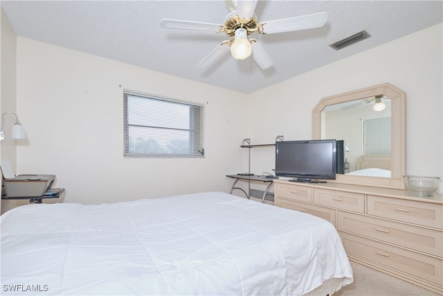 carpeted bedroom featuring ceiling fan and a textured ceiling