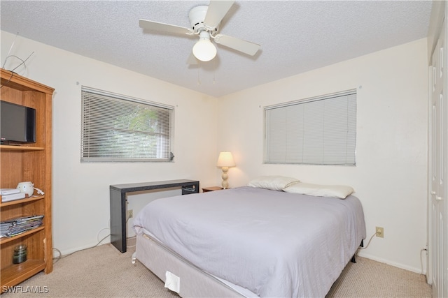 carpeted bedroom featuring ceiling fan and a textured ceiling