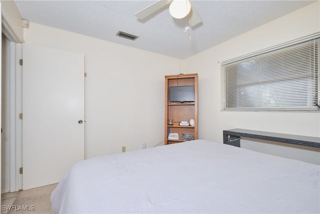 carpeted bedroom with ceiling fan and a textured ceiling