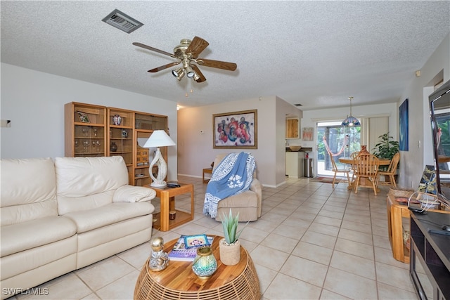 living room featuring light tile patterned flooring, ceiling fan, and a textured ceiling