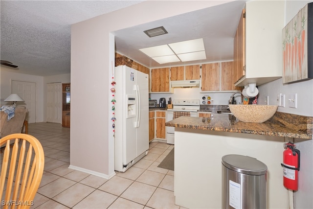 kitchen featuring light tile patterned floors, white appliances, kitchen peninsula, a textured ceiling, and dark stone counters