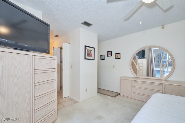 bedroom with ceiling fan, light colored carpet, and a textured ceiling