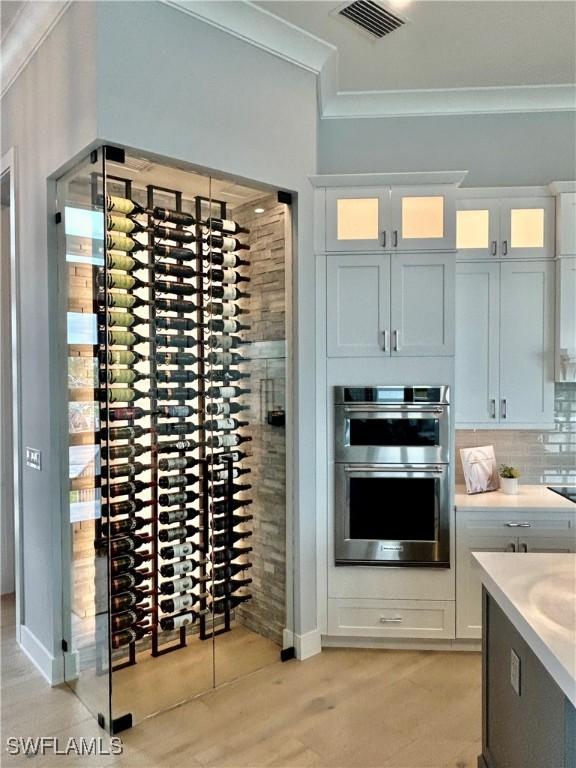 wine cellar with crown molding and light wood-type flooring