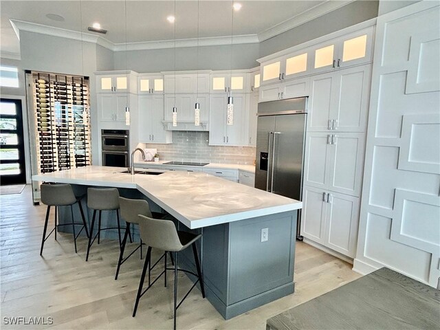 kitchen featuring sink, white cabinets, a kitchen bar, a center island with sink, and stainless steel appliances