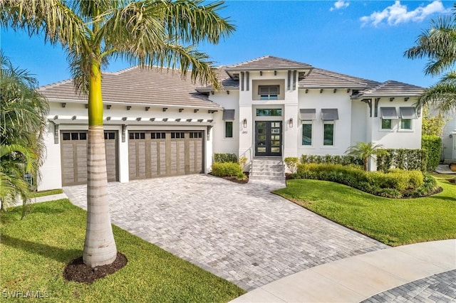 mediterranean / spanish-style house with a garage, a front yard, and french doors