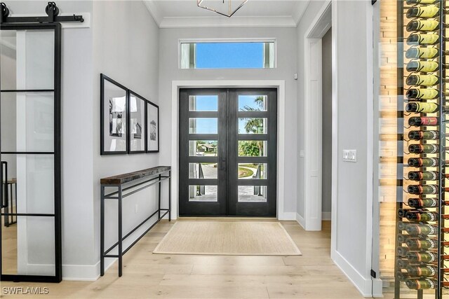 entryway featuring light wood-type flooring, french doors, and crown molding