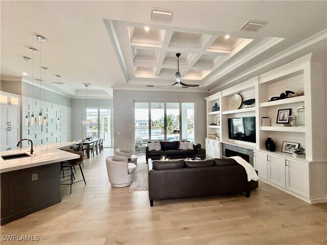 living room featuring beamed ceiling, crown molding, coffered ceiling, sink, and ceiling fan