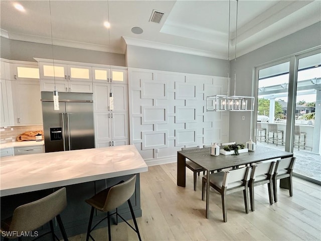 kitchen with a tray ceiling, white cabinets, and stainless steel built in fridge