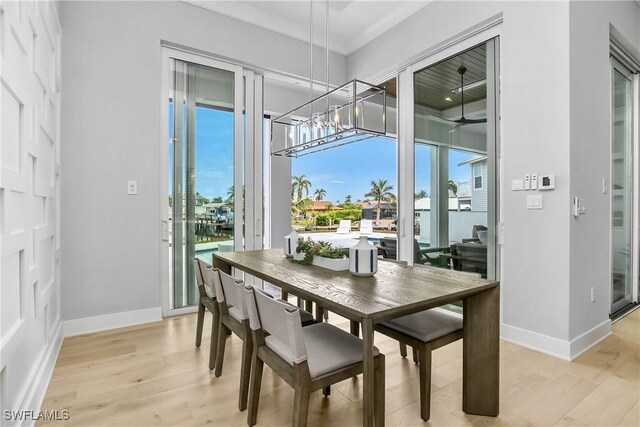 dining space with light hardwood / wood-style flooring, ornamental molding, and a chandelier