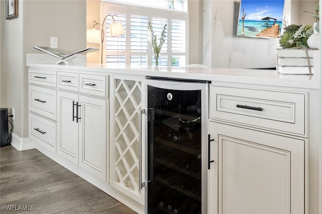 bar with beverage cooler, hardwood / wood-style floors, and white cabinetry