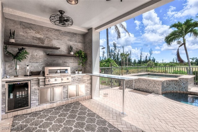 view of patio / terrace with an in ground hot tub, an outdoor kitchen, ceiling fan, beverage cooler, and area for grilling