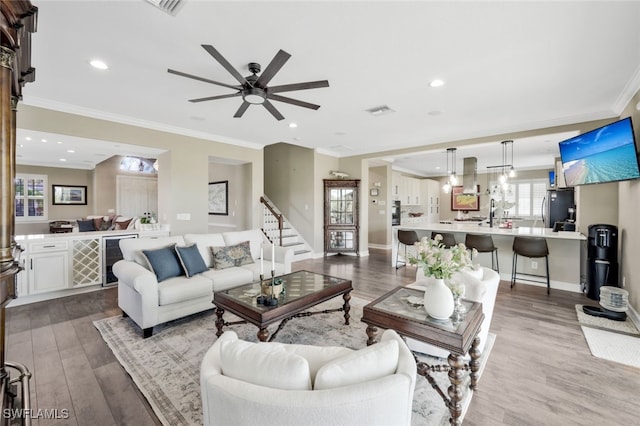 living room with ornamental molding, ceiling fan, and wood-type flooring