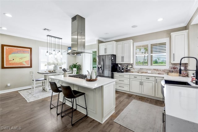 kitchen featuring island range hood, stainless steel appliances, a kitchen island, white cabinets, and decorative light fixtures