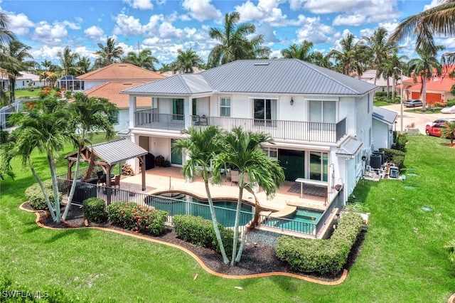 back of property featuring a yard, a gazebo, a balcony, a fenced in pool, and a patio area