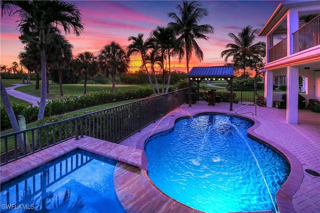 pool at dusk featuring area for grilling and a patio