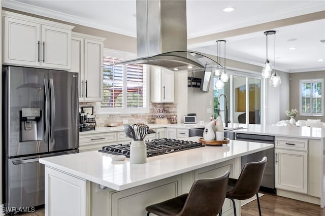 kitchen featuring appliances with stainless steel finishes, island exhaust hood, crown molding, and a kitchen island