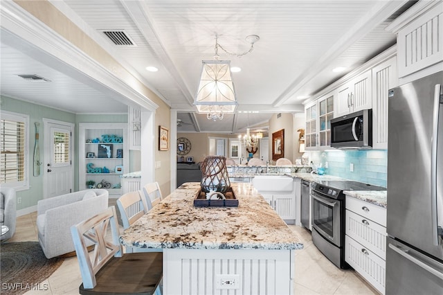 kitchen with decorative light fixtures, a kitchen bar, stainless steel appliances, an inviting chandelier, and kitchen peninsula